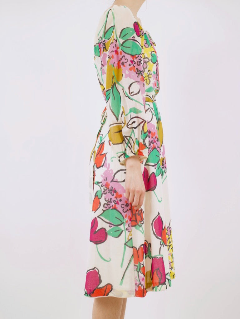 the side of a vintage 1960's blouson style dress with a tied wait, long sleeves and a whimsical floral pattern