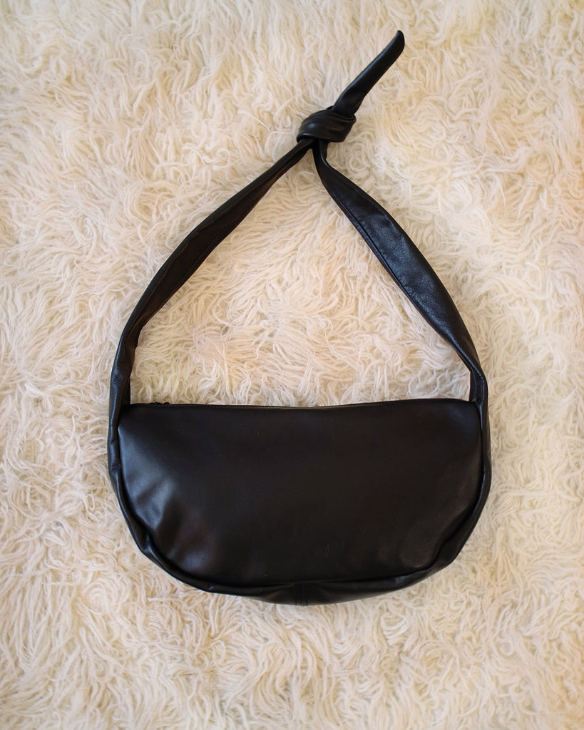 a large leather sling style handbag shown in black leather with a knotted strap and double zip closure, handmade by erin templeton in vancouver, canada