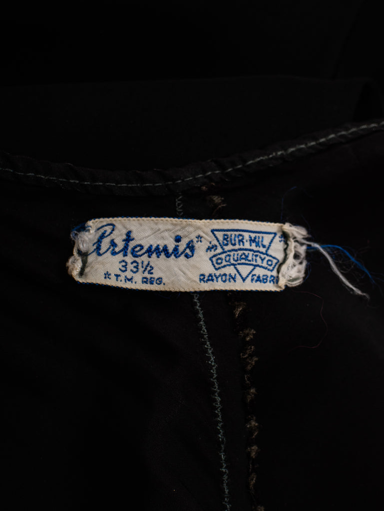 closeup of the label of a black 1940's ARTEMIS contrast stitch rayon knee length slip dress