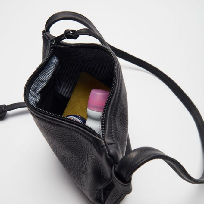 the interior of a small black leather purse with zip closure, a hickory stripe lining and an inner leather zip pocket and miscellaneous contents, handmade by erin templeton in vancouver, canada