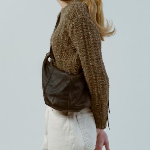 a large hobo leather purse in brown leather with a zip closure, worn crossbody on a model  in front of a white background