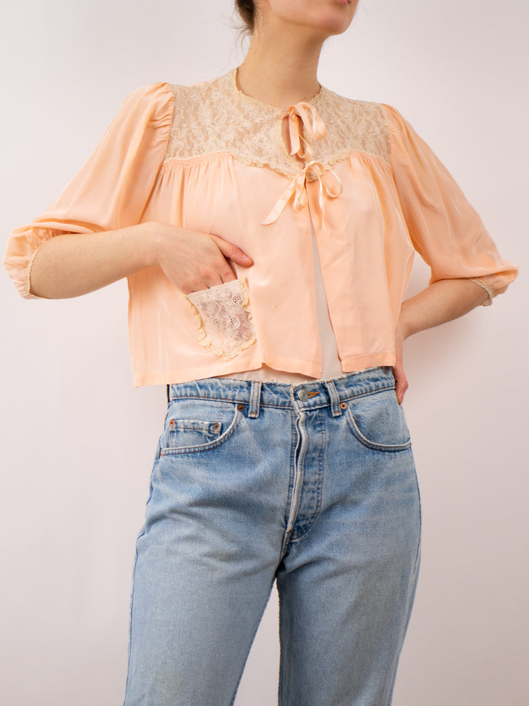 peach 1940's bed jacket with lace pockets and yoke and a ribbon tie closure