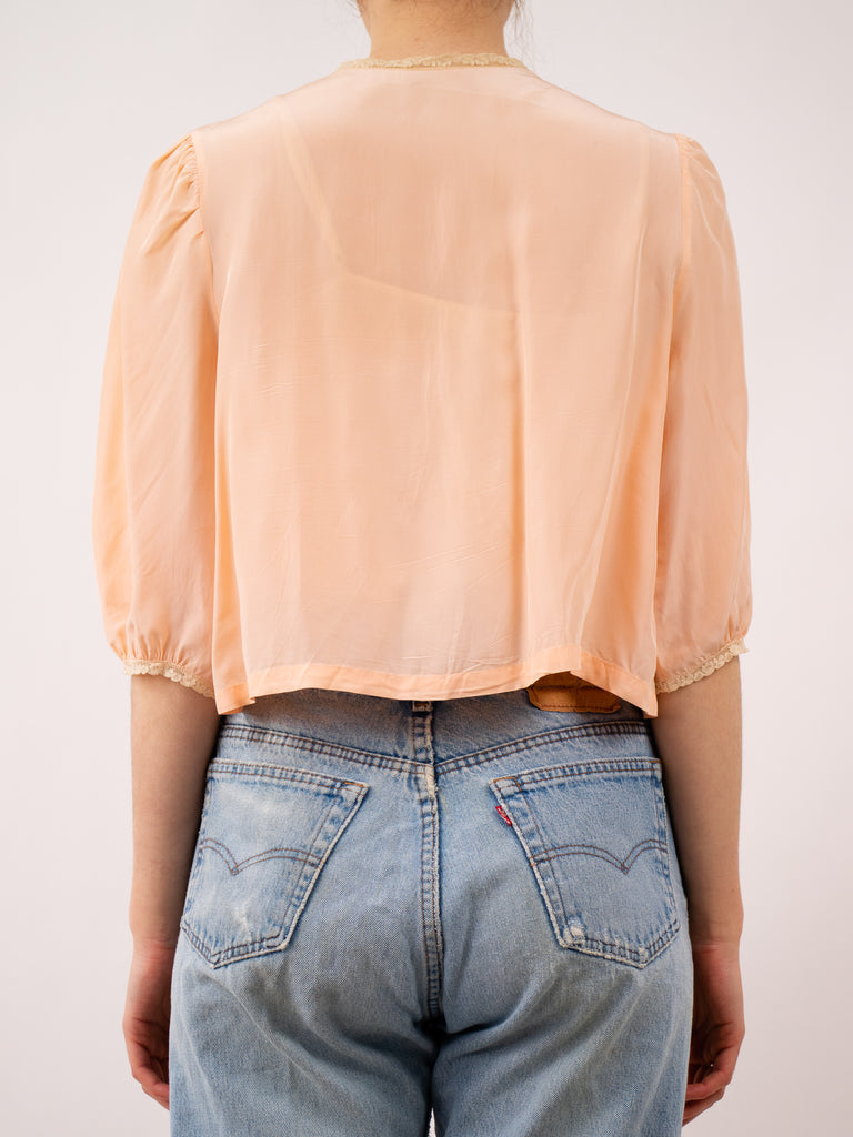 back view of peach 1940's bed jacket with lace pockets and yoke and a ribbon tie closure