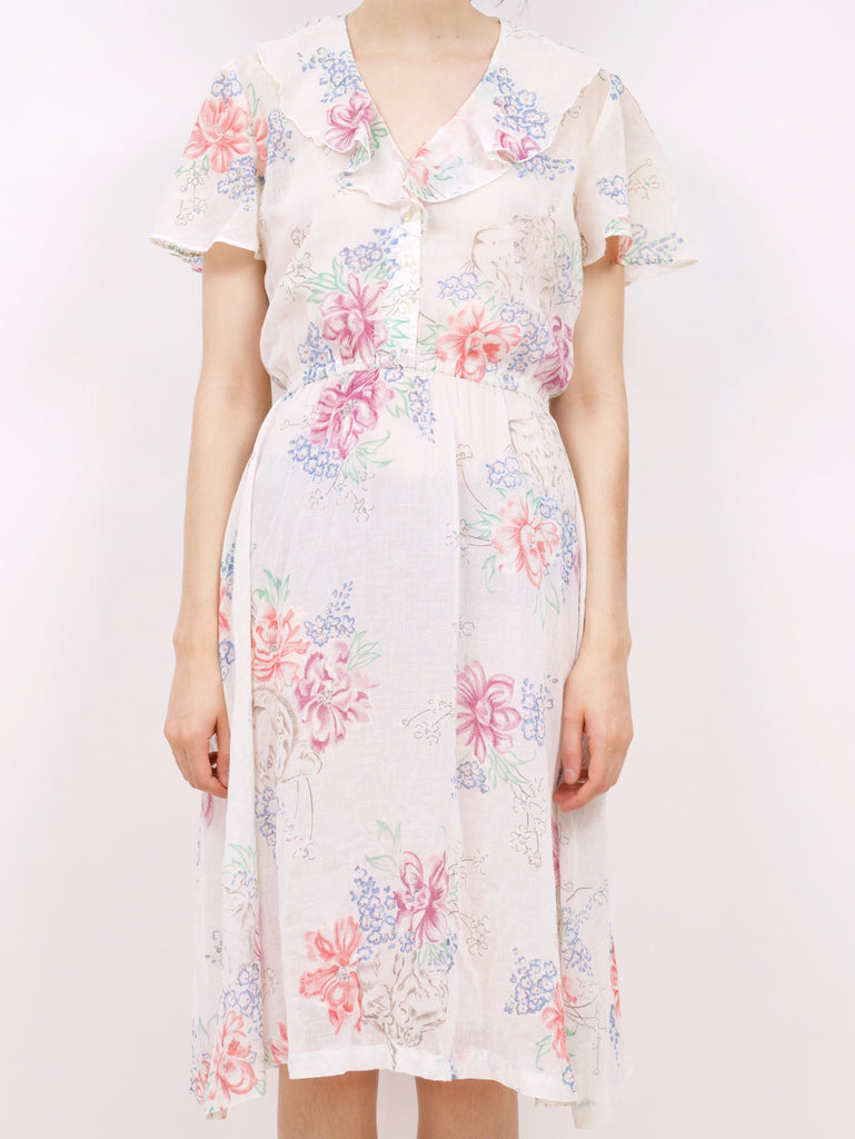 the front of a blouson style dress with a floral pattern and ruffle details