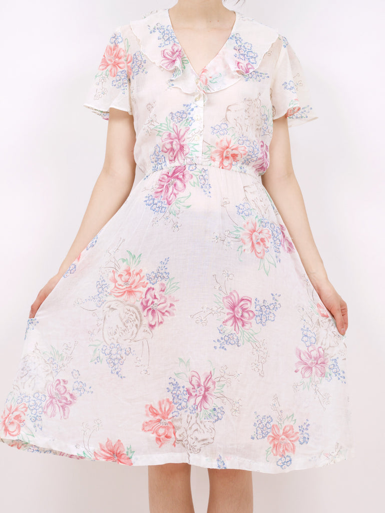 the front of a blouson style dress with a floral pattern and ruffle details