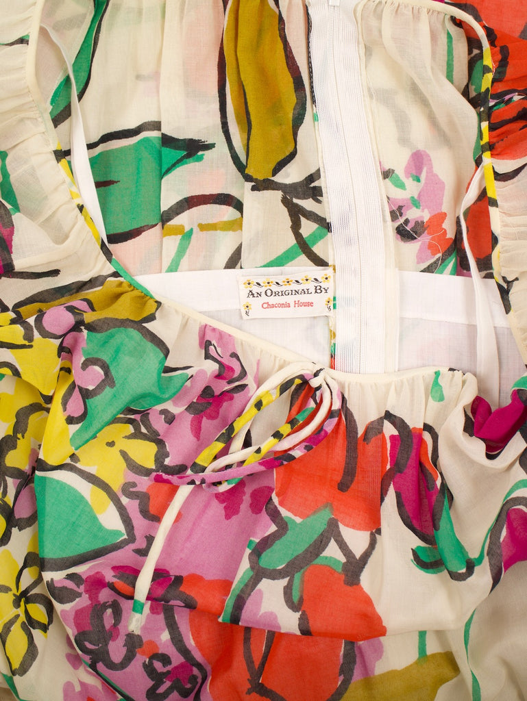 the tag of a vintage 1960's blouson style dress with a zipper in the back and a whimsical floral pattern
